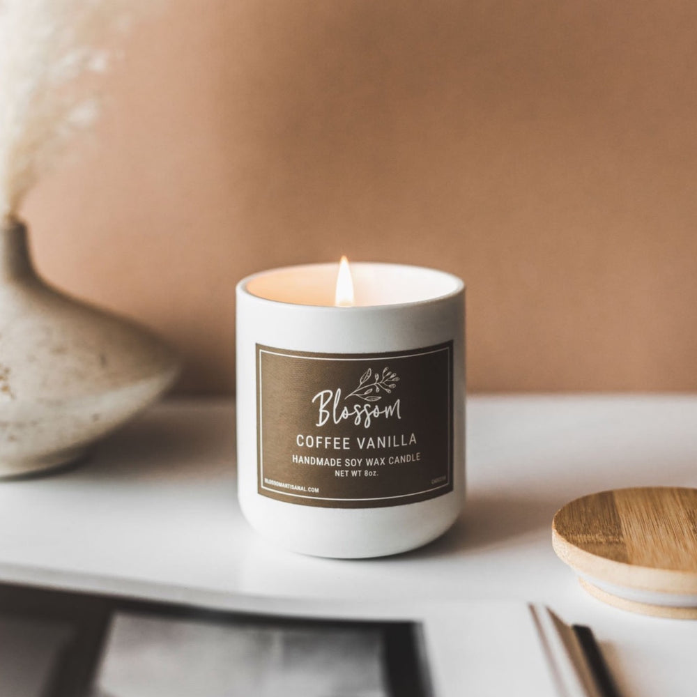 Beautiful white ceramic coffee vanilla candle with brown label on table with light brown background